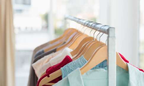 木製ハンガーに掛かった色とりどりの服とラック