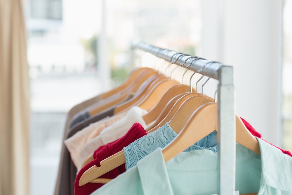 木製ハンガーに掛かった色とりどりの服とラック