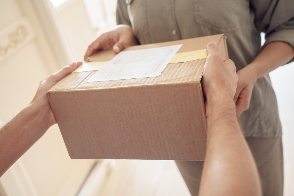 玄関先で段ボールの荷物を両手で受け取る手元