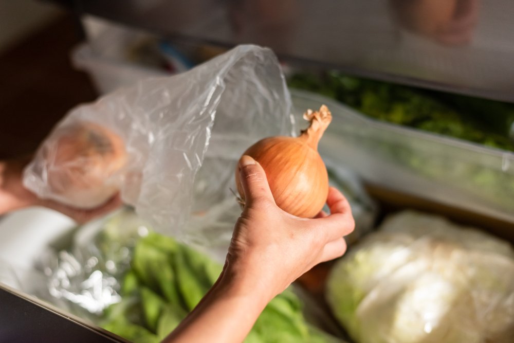 冷蔵庫の野菜室から玉ねぎを取り出す手元