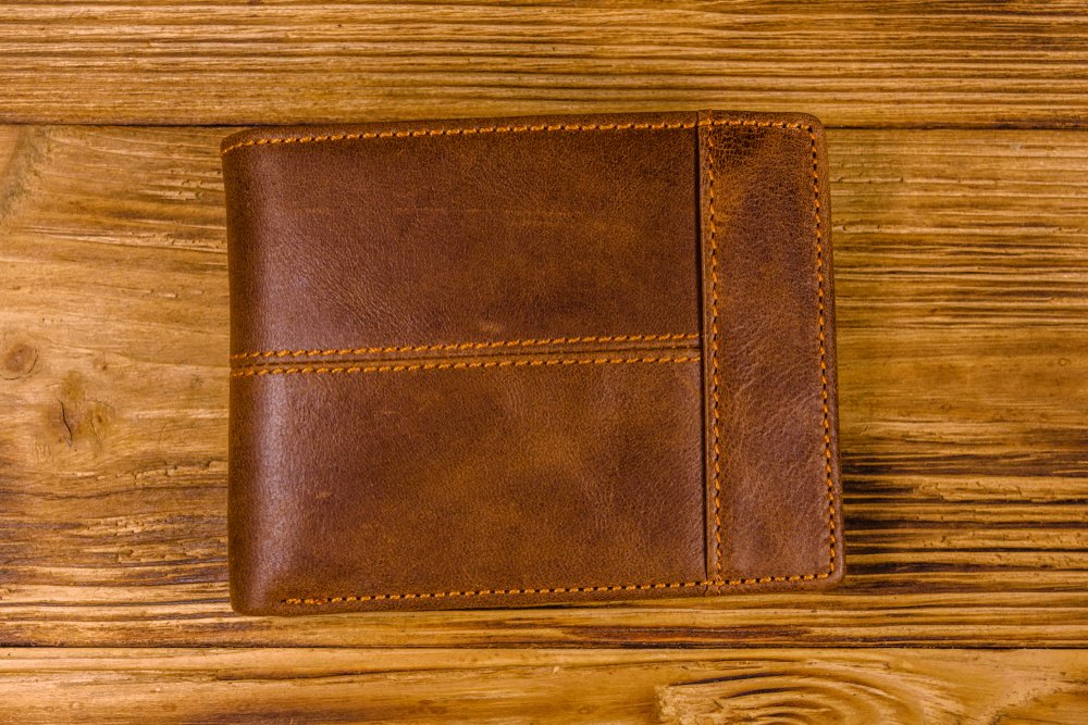 木のテーブルに置かれた茶色い革の財布