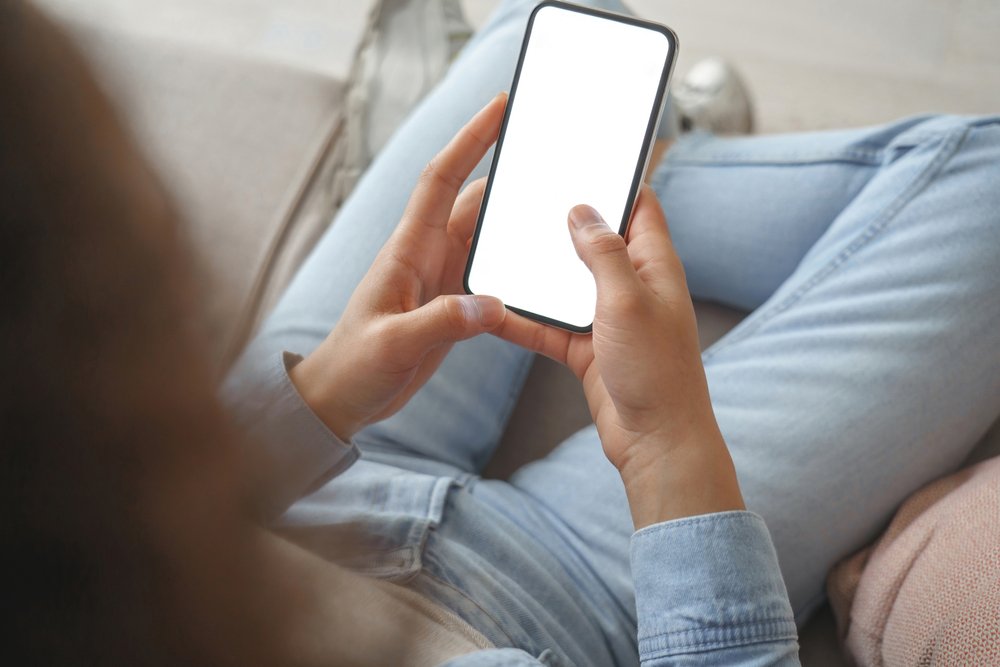 ソファでくつろぎながらスマートフォンを操作する手元