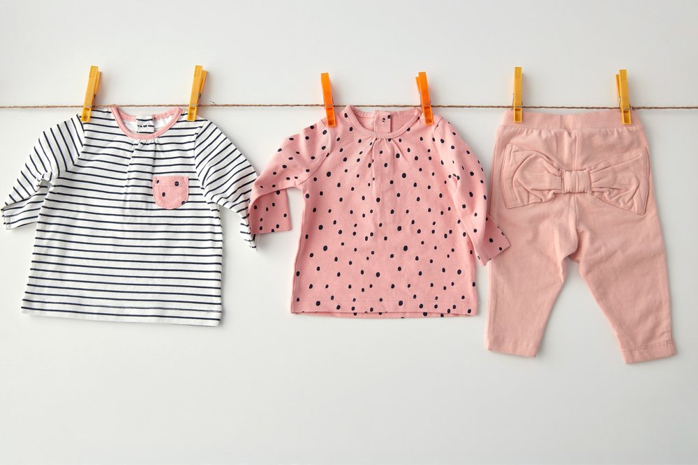 洗濯ばさみで物干しロープに干された子ども服の上下