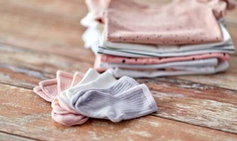 木のテーブルに畳んで重ねた綿の服と靴下
