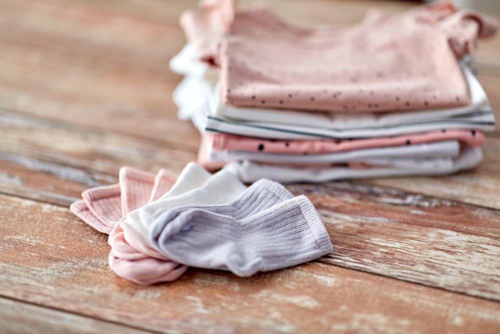木のテーブルに畳んで重ねた綿の服と靴下