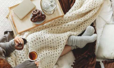 ニットのブランケットと毛糸の靴下で温まりながら紅茶を持つ手元