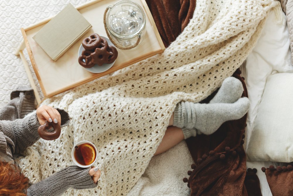 ニットのブランケットと毛糸の靴下で温まりながら紅茶を持つ手元